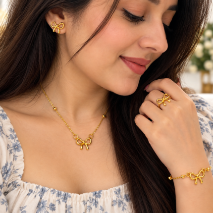 Woman wearing a gold-tone bow necklace, earrings, bracelet and ring