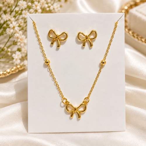 Gold-tone bow necklace and matching bow stud earrings on a display card