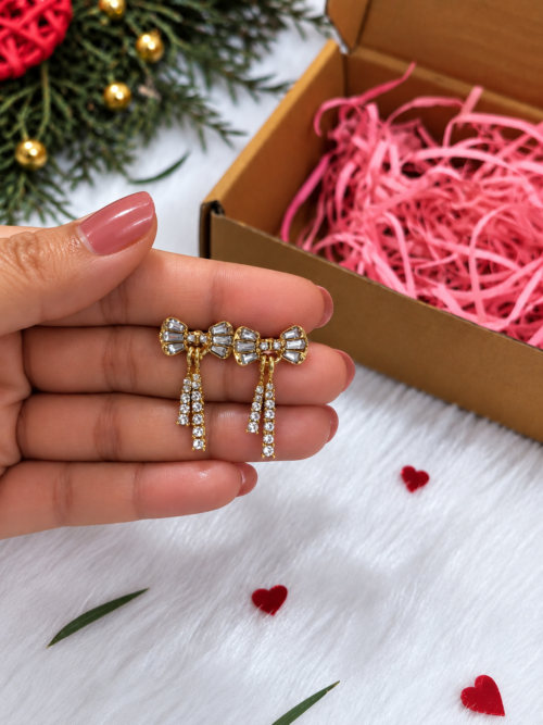 Close-up of gold-tone bow earrings with sparkling hanging strands