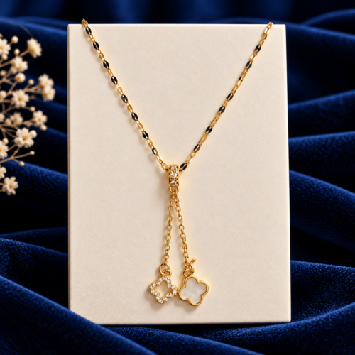 Golden Clover Necklace with twin dangling clover charms and clear stones on an ivory display