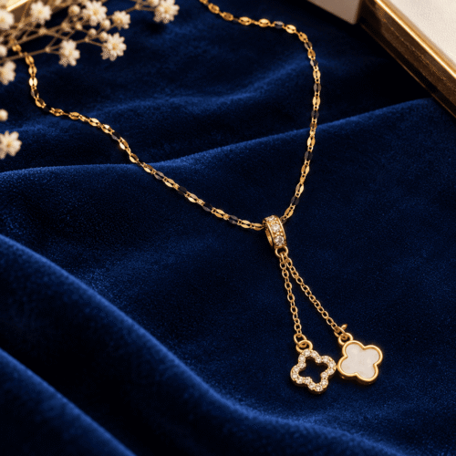Full view of Golden Clover Necklace with a gold-tone chain and white and clear-stone clover charms on navy velvet