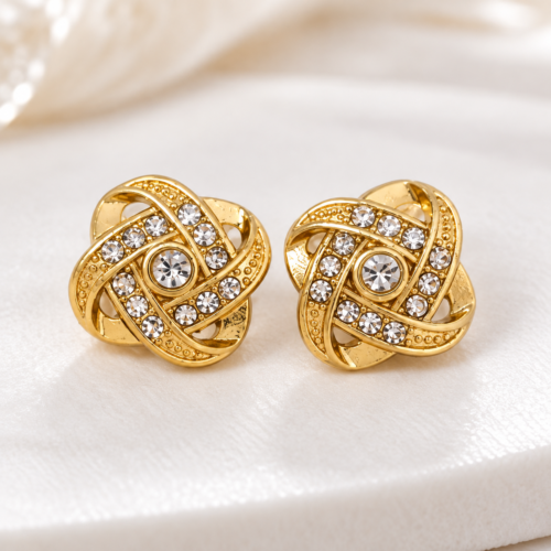 Pair of gold-tone knot stud earrings on a cream surface