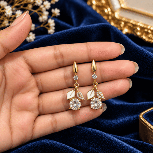 Pair of Golden Leaf Earrings with white leaf details and clear stones held in an open palm