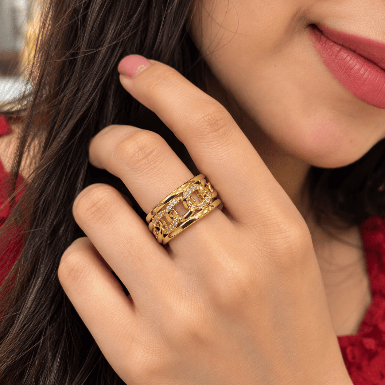 Golden Link Ring Worn by Woman Woman wearing a gold-tone ring with chain-link details and clear stones