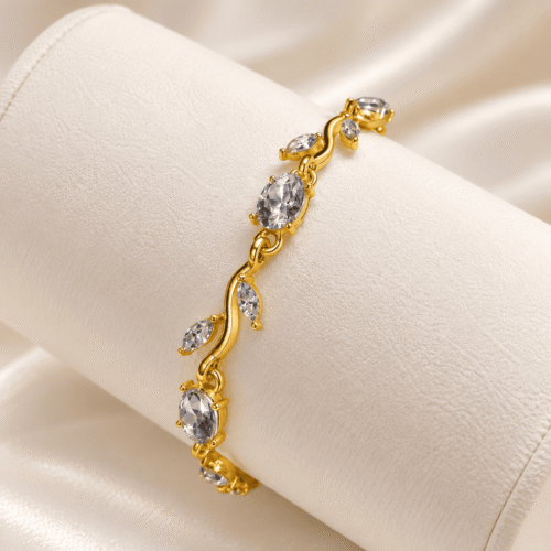 Gold-tone vine bracelet with clear oval and leaf-shaped stones on an ivory cushion