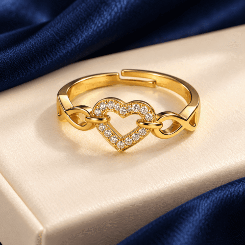 Gold-tone heart and infinity ring showing its open-ended band against ivory velvet and navy satin
