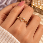 Gold-tone open-heart ring with clear stones and infinity links worn on a finger