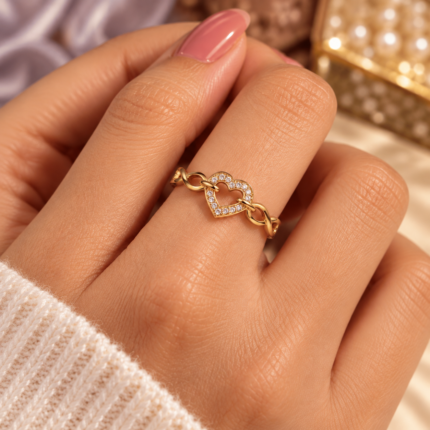 Gold-tone open-heart ring with clear stones and infinity links worn on a finger
