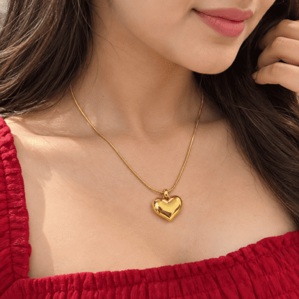 Lustrous Heart Necklace with a polished gold-tone heart pendant worn by a woman in a red dress