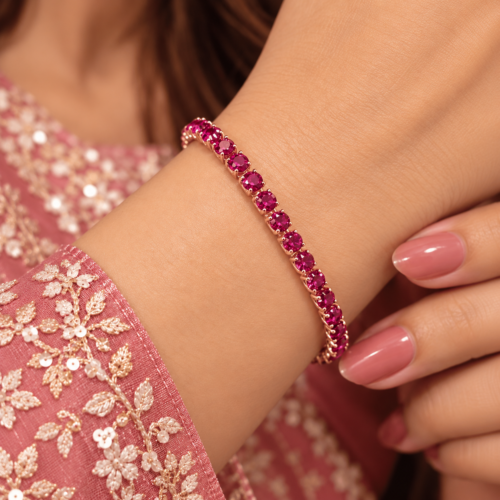 Woman wearing a rose gold-tone bracelet with a single row of round magenta-pink stones
