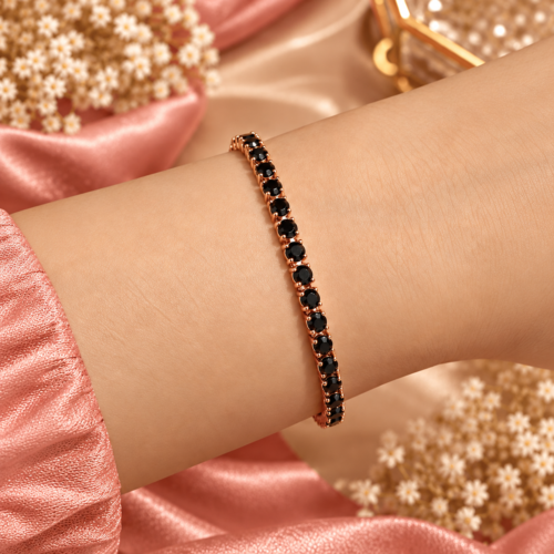 Rose gold-tone bracelet with round black stones worn on a wrist