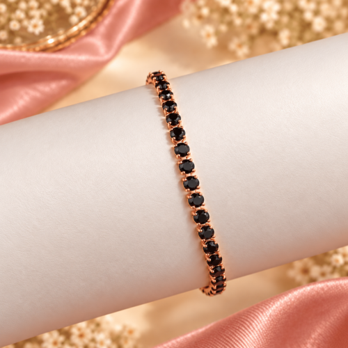 Round black stones in rose gold-tone bracelet settings on an ivory display
