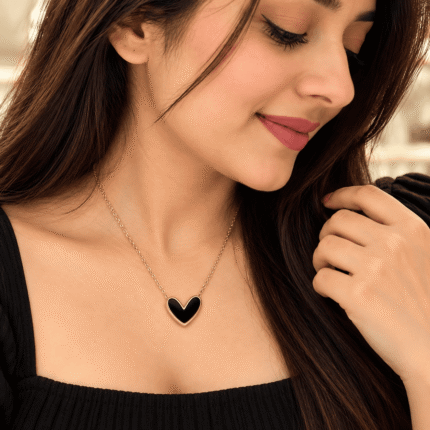 Woman wearing a black heart necklace with a gold-tone border and chain