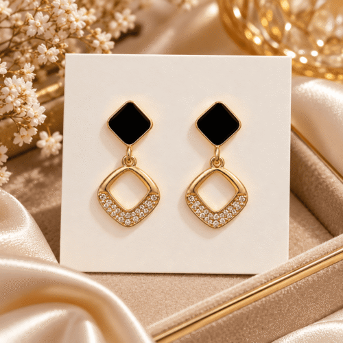 Pair of Midnight Square Earrings with black square tops and clear stone accents on an ivory display