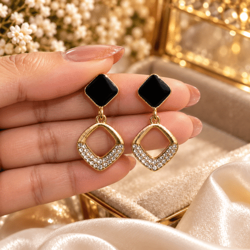 Pair of Midnight Square Earrings with black square tops and sparkling open square drops held in a hand