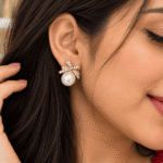 Woman wearing a gold-tone sparkling bow earring with a white pearl-style bead