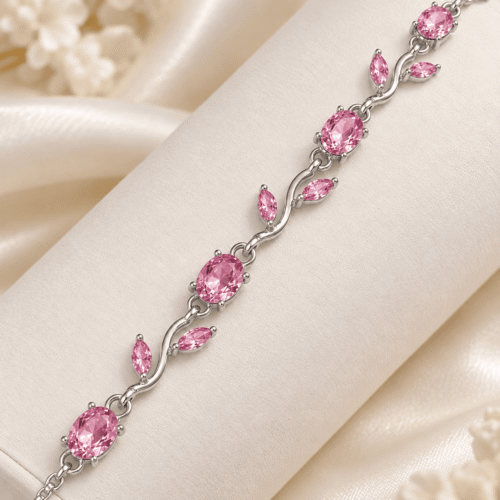 Close-up of pink oval stones and silver-tone vine and leaf details on a bracelet