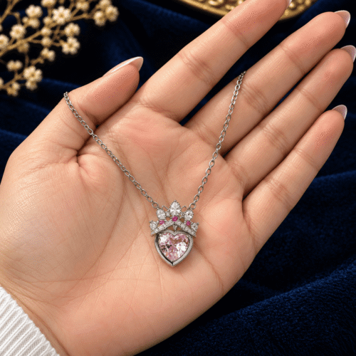 Silver-tone Princess Heart Necklace with crowned pink heart pendant held in an open palm