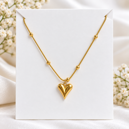 Gold-tone heart pendant necklace with round bead details on a white display card