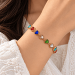 Woman wearing a gold-tone bracelet with linked multicolour heart-shaped stones