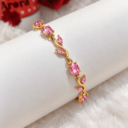 Rosy Vine Bracelet with pink stones and gold-tone finish on an ivory display cushion
