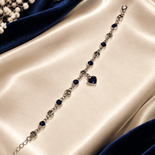 Open view of Sapphire Heart Bracelet showing round stones, silver-tone chain links, clasp and hanging heart charm