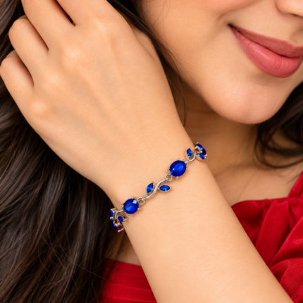 Woman wearing a silver-tone vine bracelet with blue oval stones and leaf details
