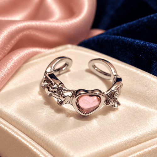 Front detail of a silver-tone ring with a pink heart centre and sculpted floral sides