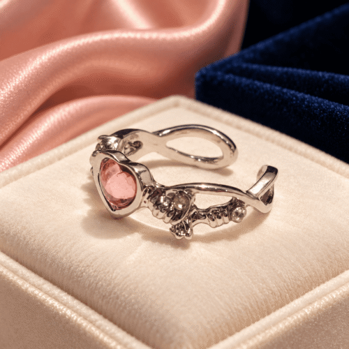 Side detail of an ornate pink heart ring showing its floral band and open-ended design