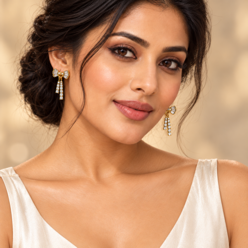 Woman wearing gold-tone bow earrings with clear stones and twin hanging strands